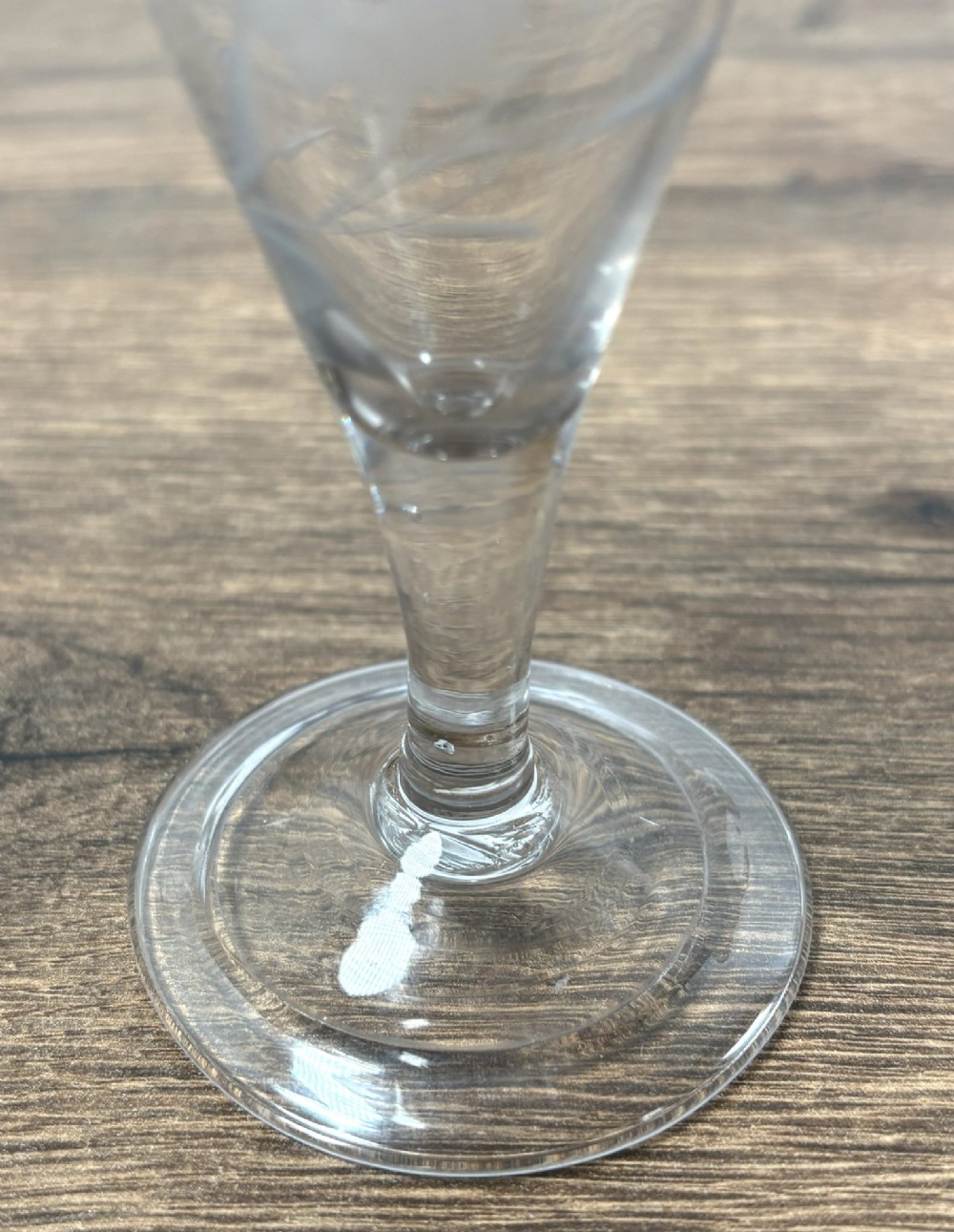 A pair of clear hand-blown Georgian glass drinking vessels featuring flared conical bowls with floral wheel engraving and circular bases. View V