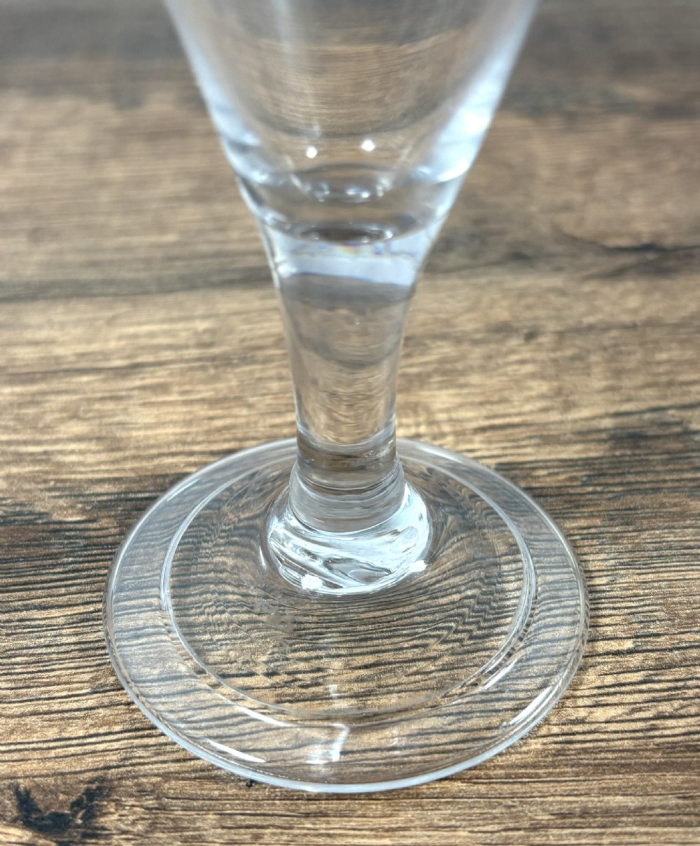 A pair of clear hand-blown Georgian glass drinking vessels featuring flared conical bowls with floral wheel engraving and circular bases. View VI