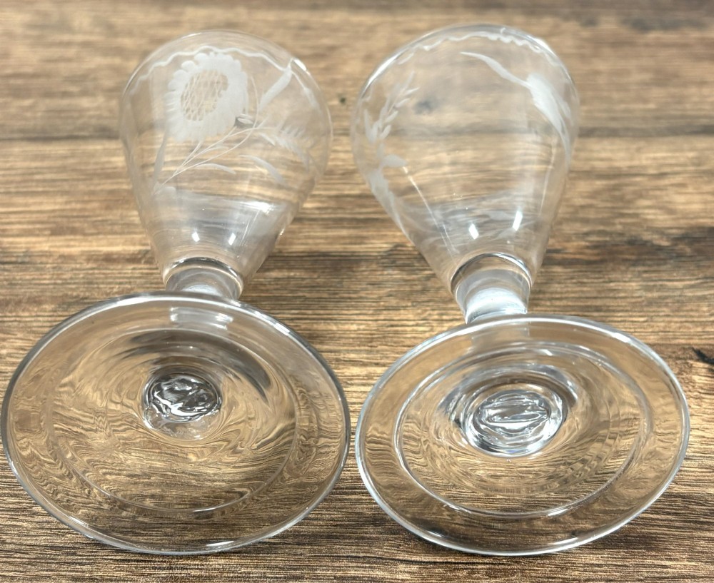 A pair of clear hand-blown Georgian glass drinking vessels featuring flared conical bowls with floral wheel engraving and circular bases. View VII