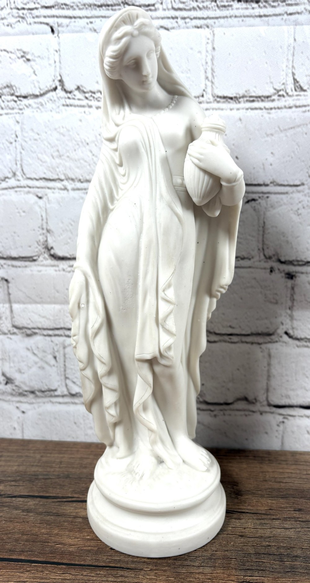 A pair of 19th-century unglazed white Parian ware porcelain figures depicting classical maidens in draped garments, standing on circular integrally moulded plinths. View II