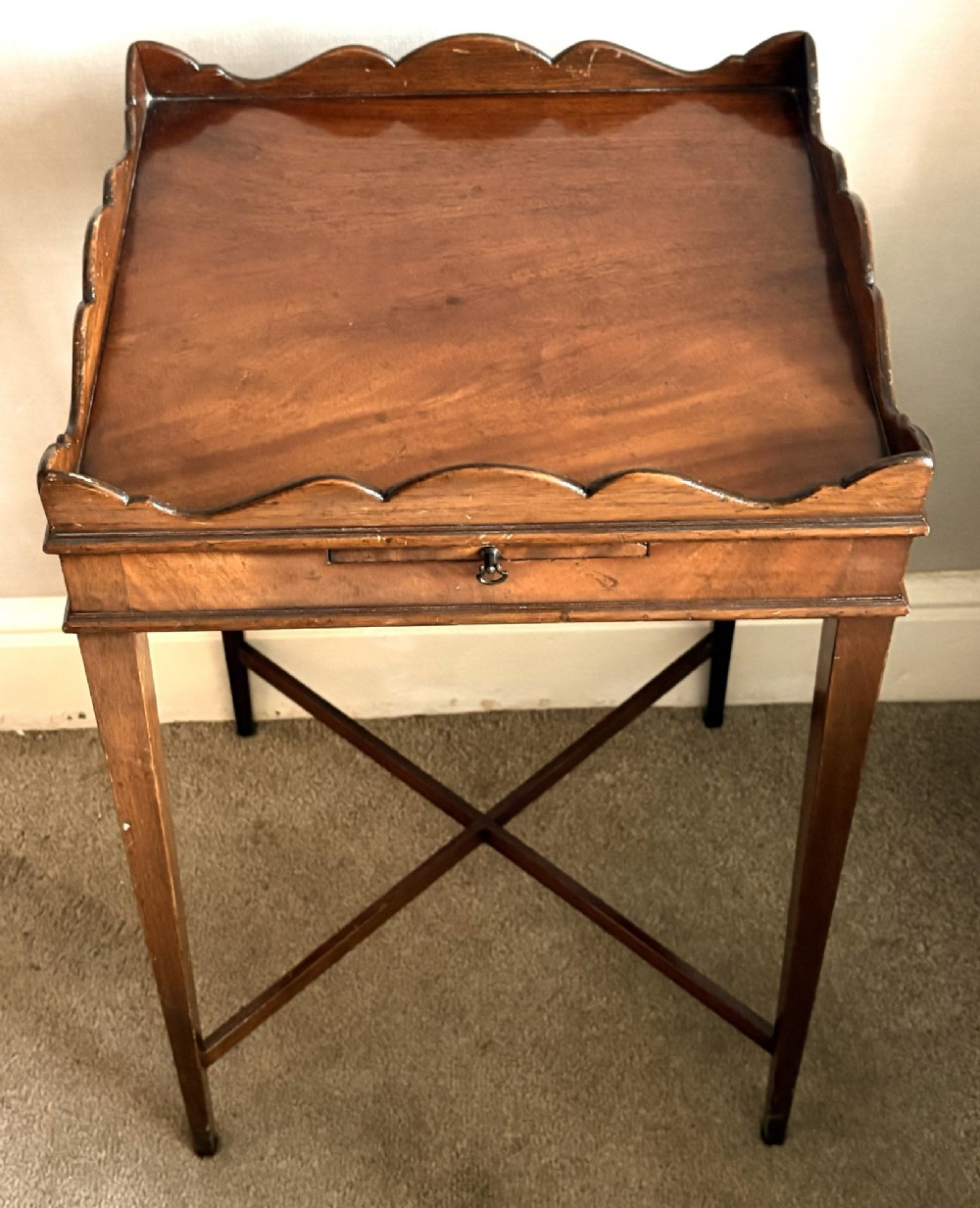 A mahogany kettle stand featuring a scalloped gallery top, a pull-out slide, slender square tapered legs, and an X-frame cross stretcher. View II