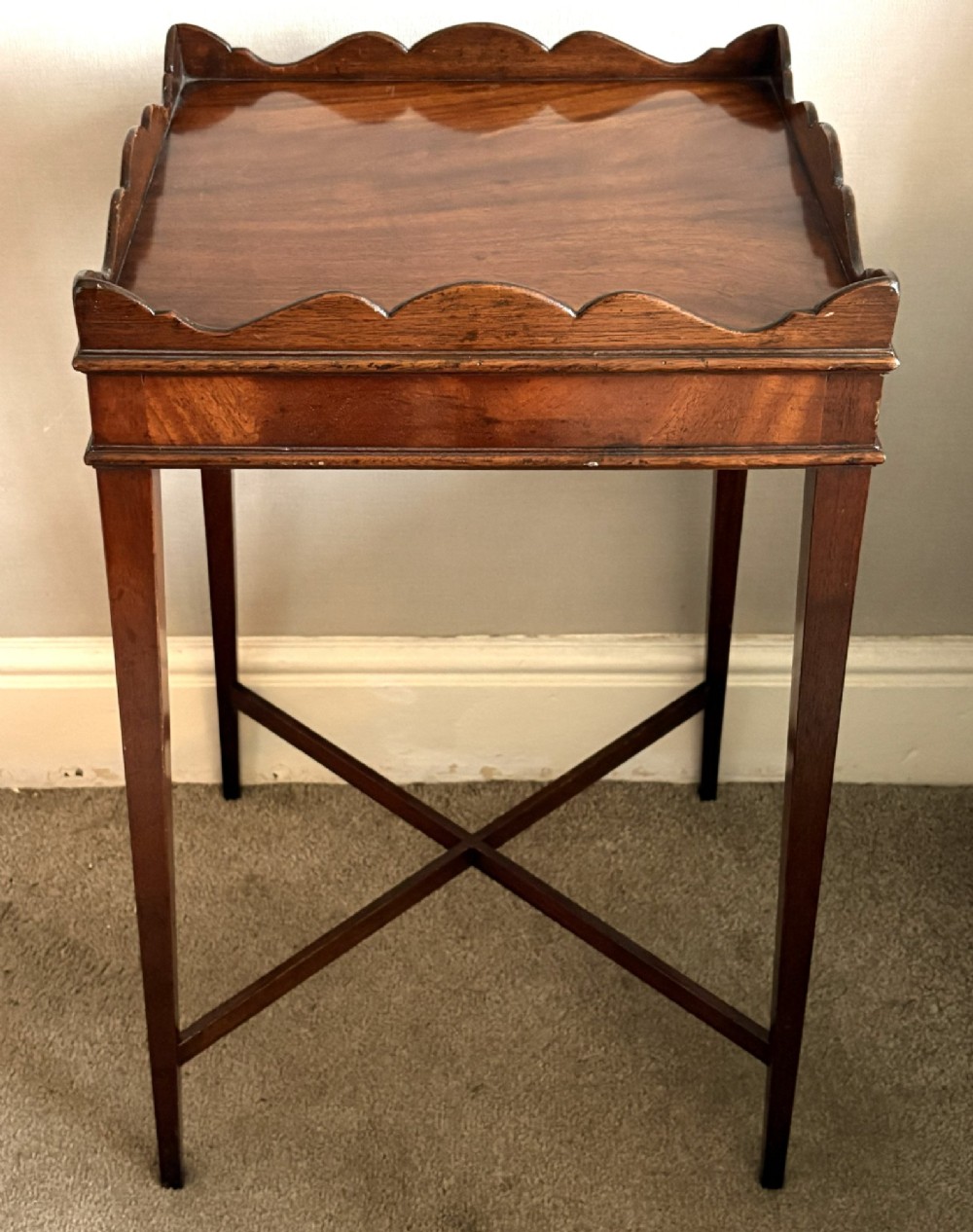 A mahogany kettle stand featuring a scalloped gallery top, a pull-out slide, slender square tapered legs, and an X-frame cross stretcher. View IV