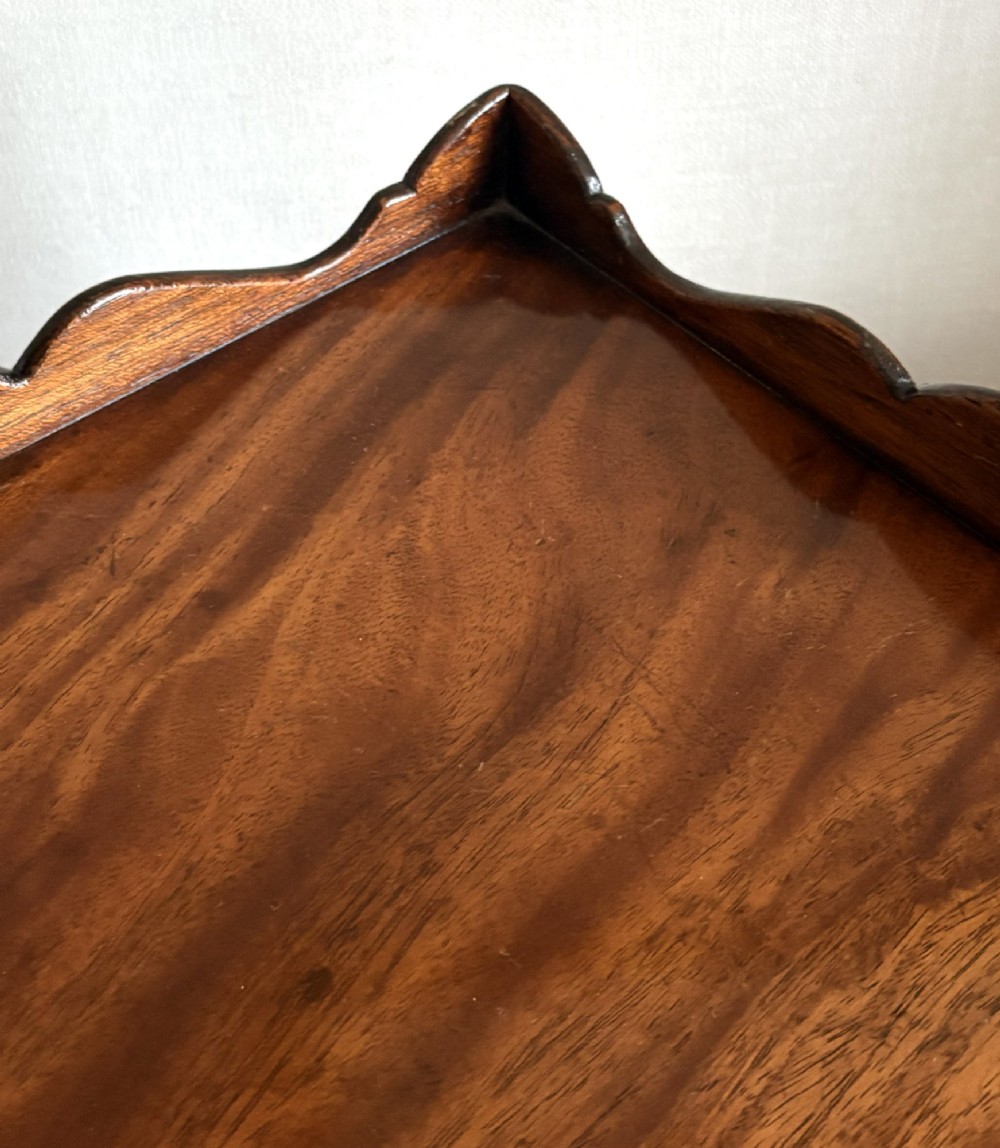 A mahogany kettle stand featuring a scalloped gallery top, a pull-out slide, slender square tapered legs, and an X-frame cross stretcher. View V