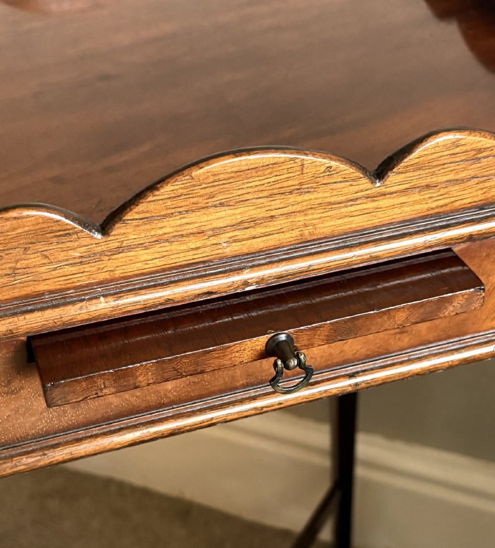 A mahogany kettle stand featuring a scalloped gallery top, a pull-out slide, slender square tapered legs, and an X-frame cross stretcher. View VI