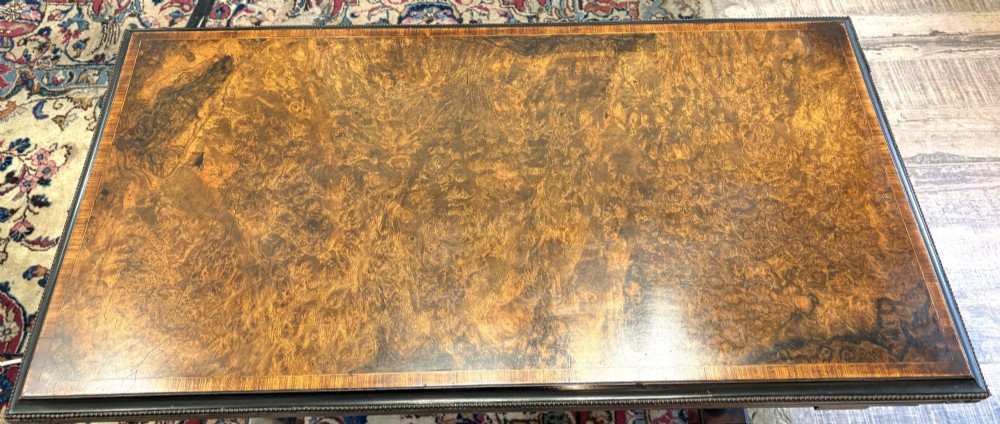 A Victorian burr walnut card table featuring ebonised bead moulding, crossbanded veneer top, twin turned pillar supports, and a turned stretcher base. View III
