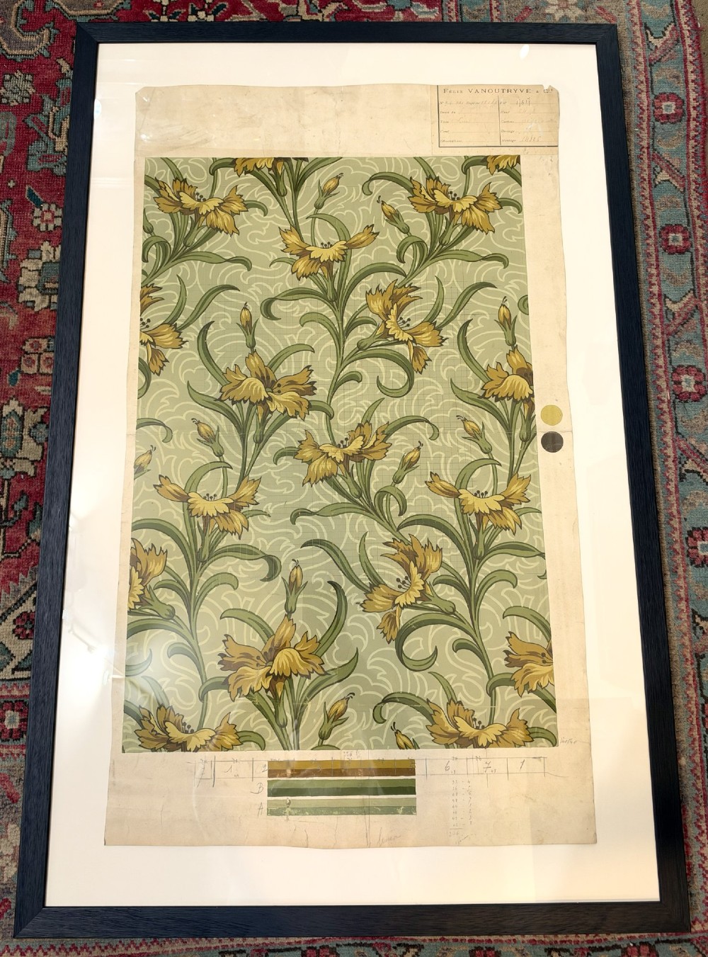 A framed Art Nouveau textile design on gridded paper featuring yellow floral motifs and green foliage against a sage background with colour swatches and technical annotations.