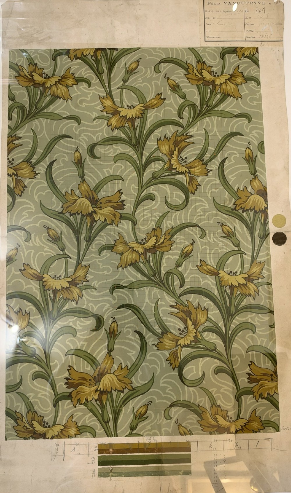 A framed Art Nouveau textile design on gridded paper featuring yellow floral motifs and green foliage against a sage background with colour swatches and technical annotations. View II