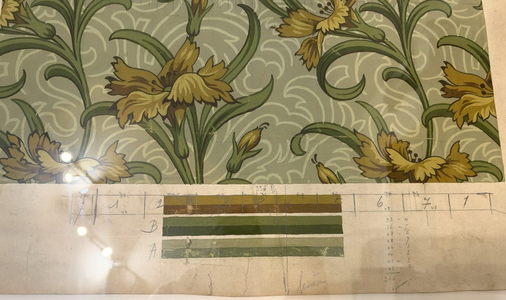 A framed Art Nouveau textile design on gridded paper featuring yellow floral motifs and green foliage against a sage background with colour swatches and technical annotations. View IV