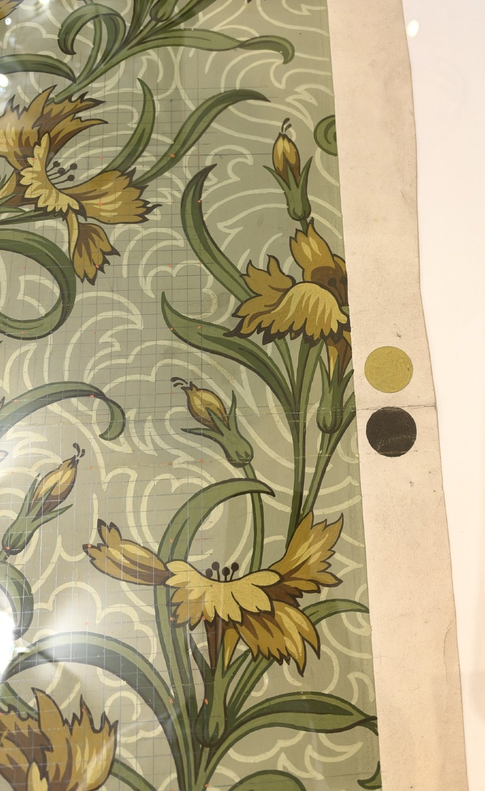 A framed Art Nouveau textile design on gridded paper featuring yellow floral motifs and green foliage against a sage background with colour swatches and technical annotations. View V