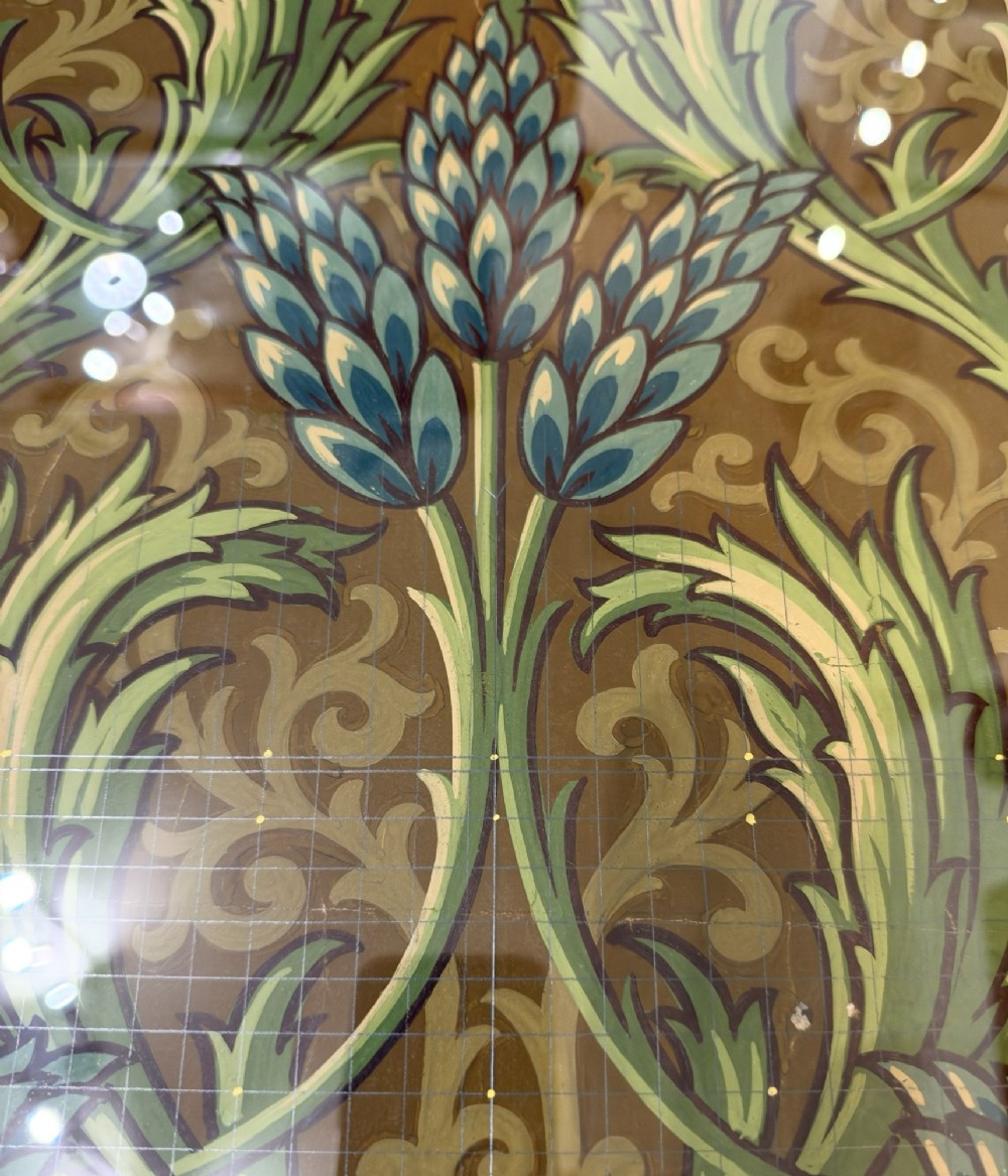 A framed antique French textile design on paper featuring stylized green leaves and blue botanical buds against a patterned brown background. View VIII