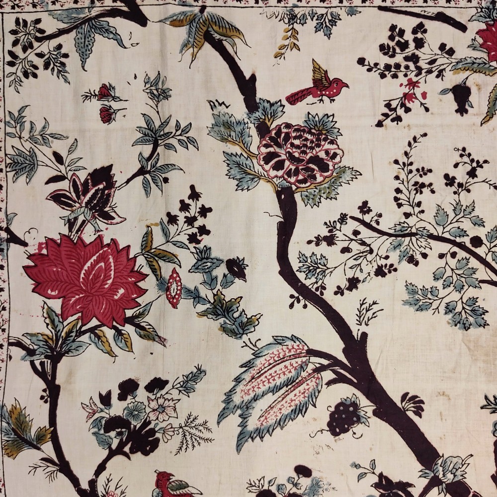 A rectangular 19th-century white cotton textile featuring a woodblock-printed tree of life design in red, green, and dark brown within an ornate floral border. View III