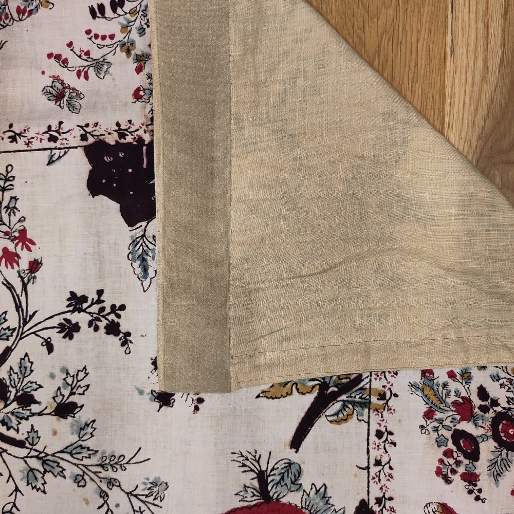 A rectangular 19th-century white cotton textile featuring a woodblock-printed tree of life design in red, green, and dark brown within an ornate floral border. View VIII
