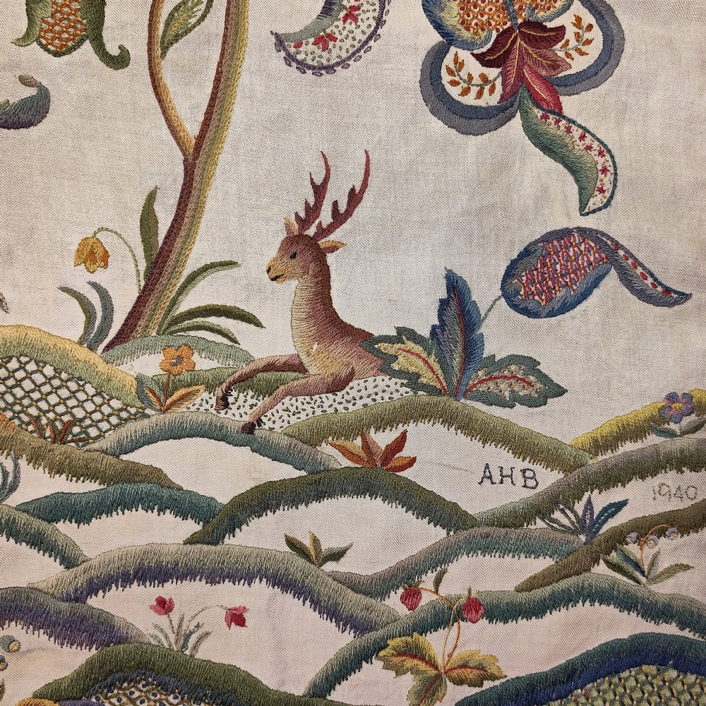 A vertical rectangular crewelwork wall hanging featuring an embroidered Tree of Life motif with scrolling vines, multicoloured flowers, birds, and a deer at the base against a cream background. View II