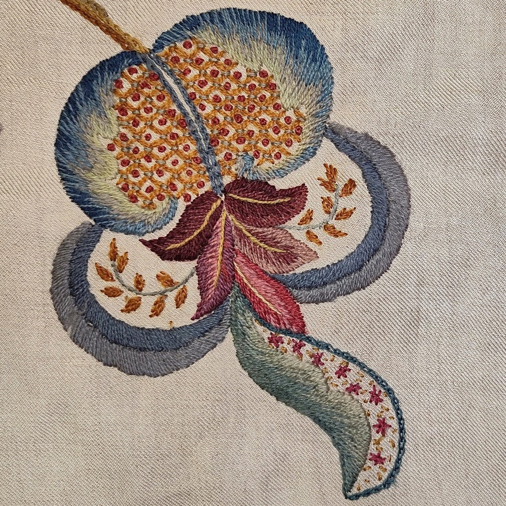 A vertical rectangular crewelwork wall hanging featuring an embroidered Tree of Life motif with scrolling vines, multicoloured flowers, birds, and a deer at the base against a cream background. View V