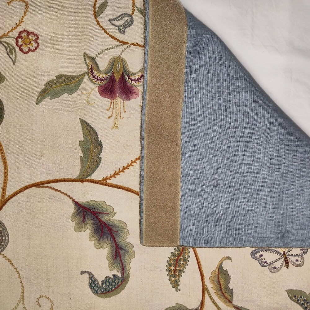 A vertical rectangular crewelwork wall hanging featuring an embroidered Tree of Life motif with scrolling vines, multicoloured flowers, birds, and a deer at the base against a cream background. View VI