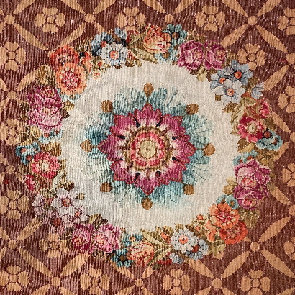 A rectangular 19th-century flatweave tapestry rug featuring a central floral medallion within a brown geometric lattice pattern. View II
