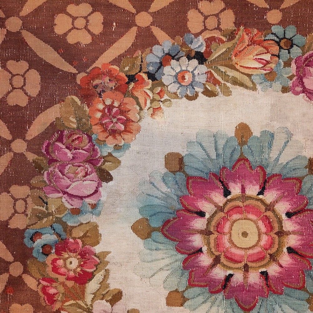 A rectangular 19th-century flatweave tapestry rug featuring a central floral medallion within a brown geometric lattice pattern. View III