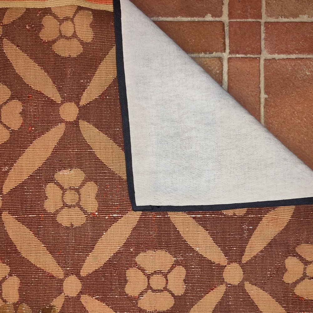 A rectangular 19th-century flatweave tapestry rug featuring a central floral medallion within a brown geometric lattice pattern. View V