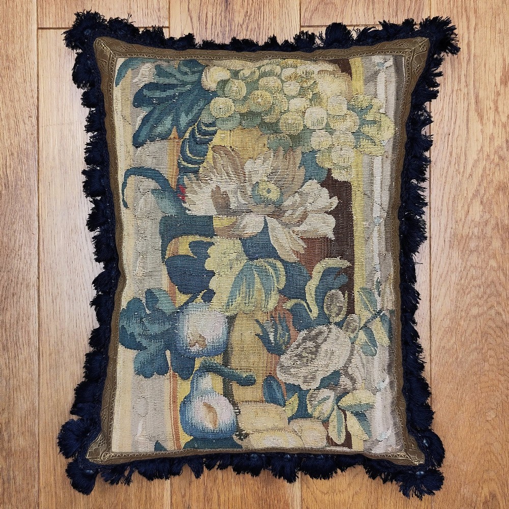 A rectangular cushion made from a seventeenth-century Flemish tapestry border featuring woven floral motifs, framed with a dark blue fringe. View II