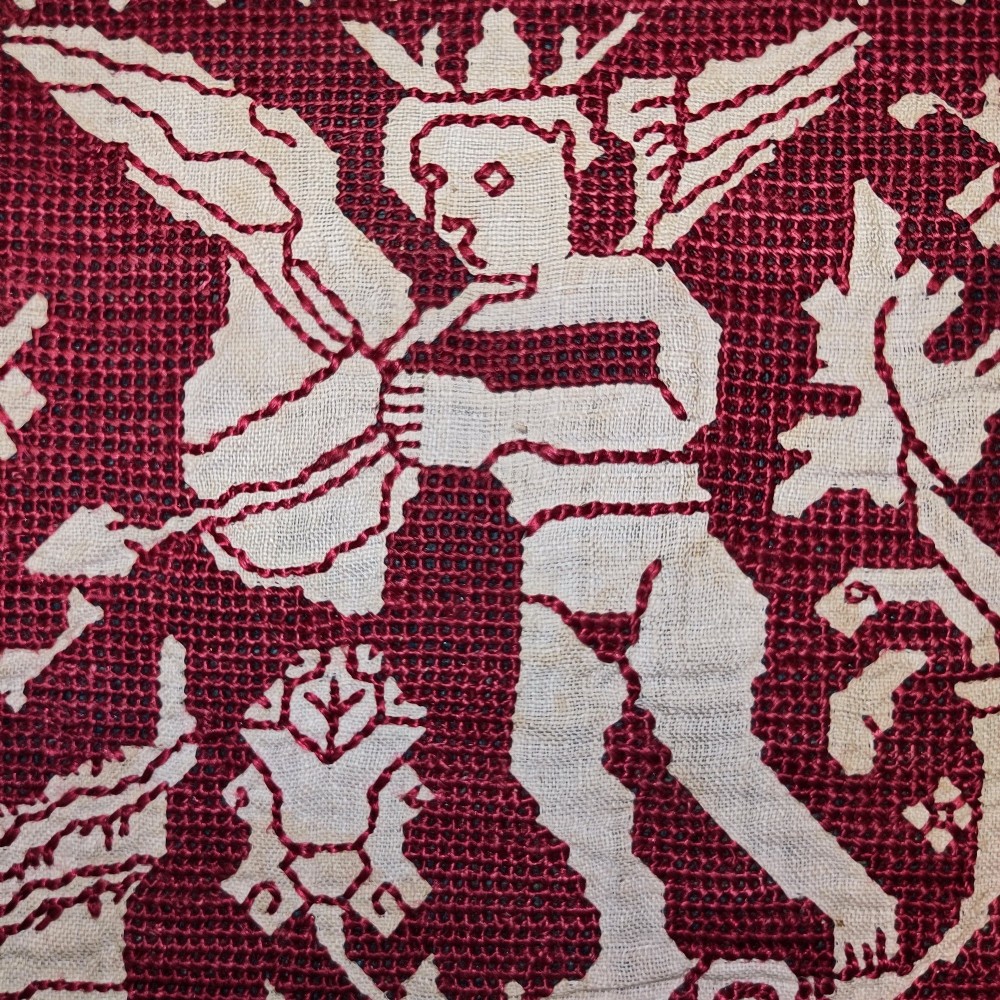 A horizontal 17th-century Italian embroidered red and cream linen border depicting winged figures and mythological creatures, mounted on blue backing within a carved gilt frame. View IV