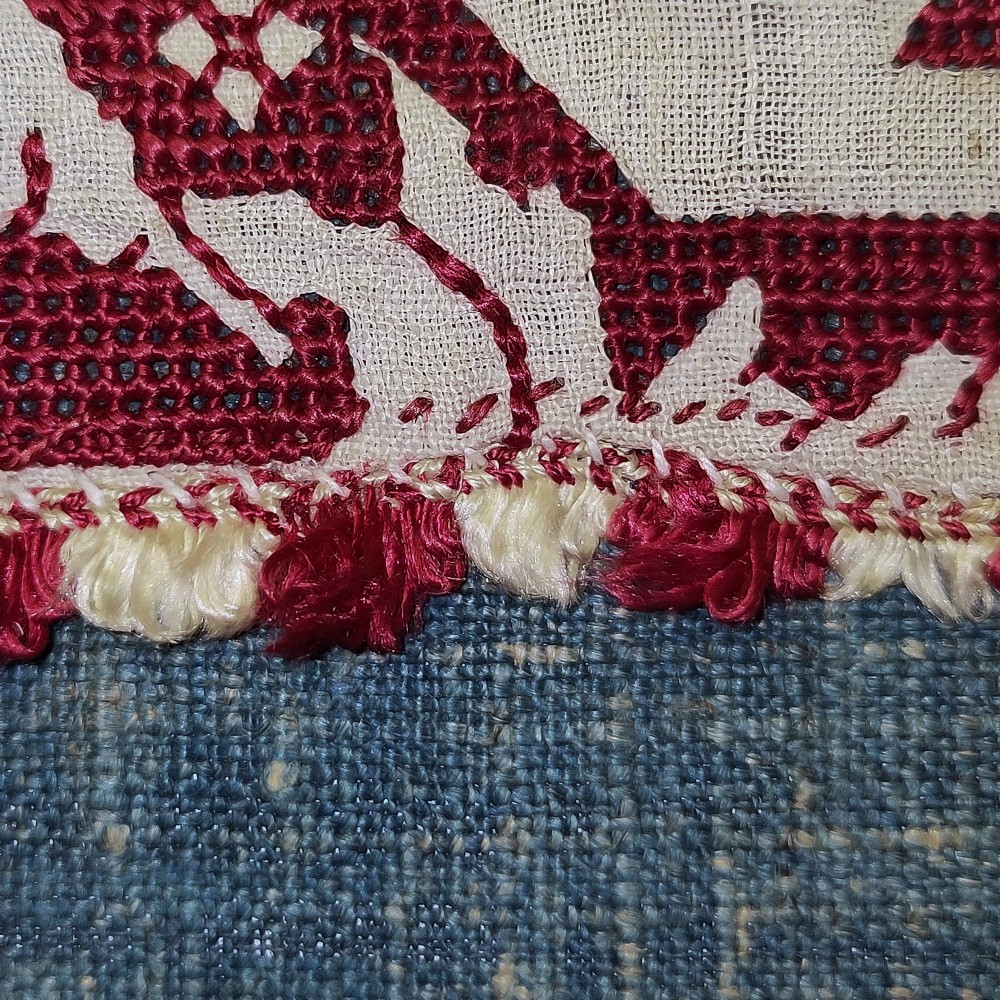 A horizontal 17th-century Italian embroidered red and cream linen border depicting winged figures and mythological creatures, mounted on blue backing within a carved gilt frame. View VI