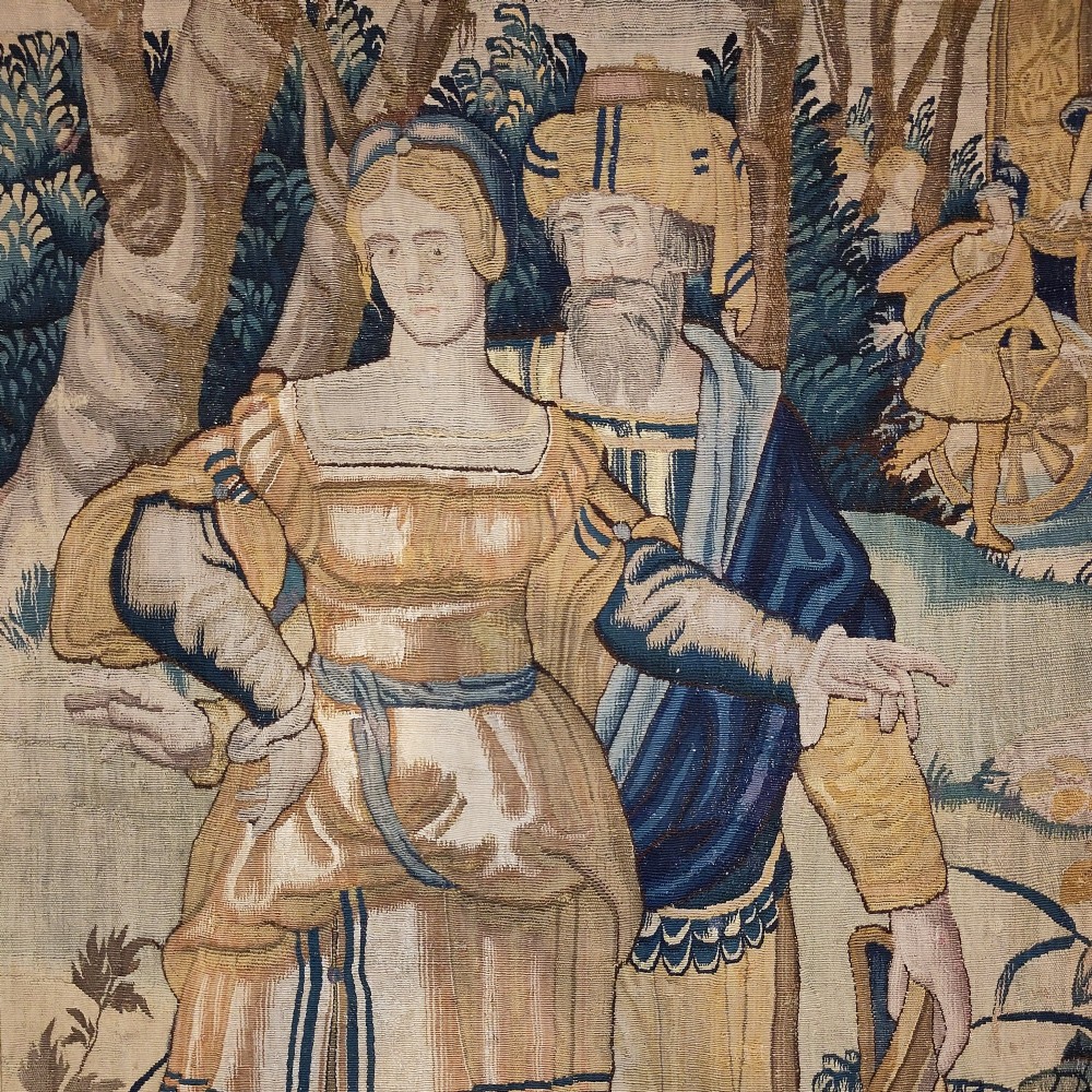 A tall rectangular Flemish tapestry panel depicting a woman and man in Renaissance attire standing in a wooded landscape. View II