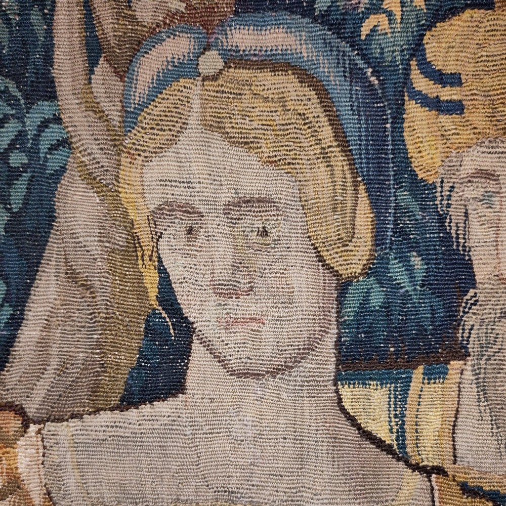 A tall rectangular Flemish tapestry panel depicting a woman and man in Renaissance attire standing in a wooded landscape. View VI