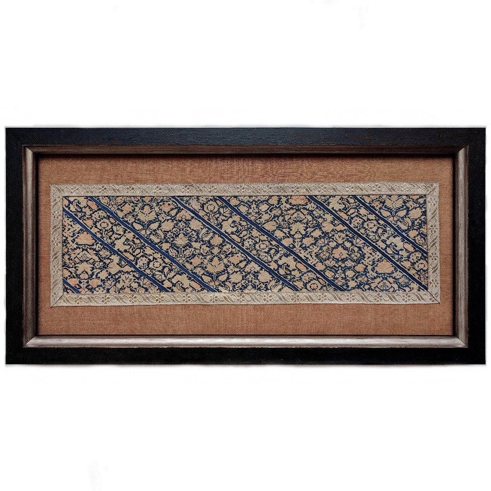 A framed rectangular panel of Persian nakshe needlework with dense diagonal floral bands in indigo blue and cream set within a dark wooden frame.