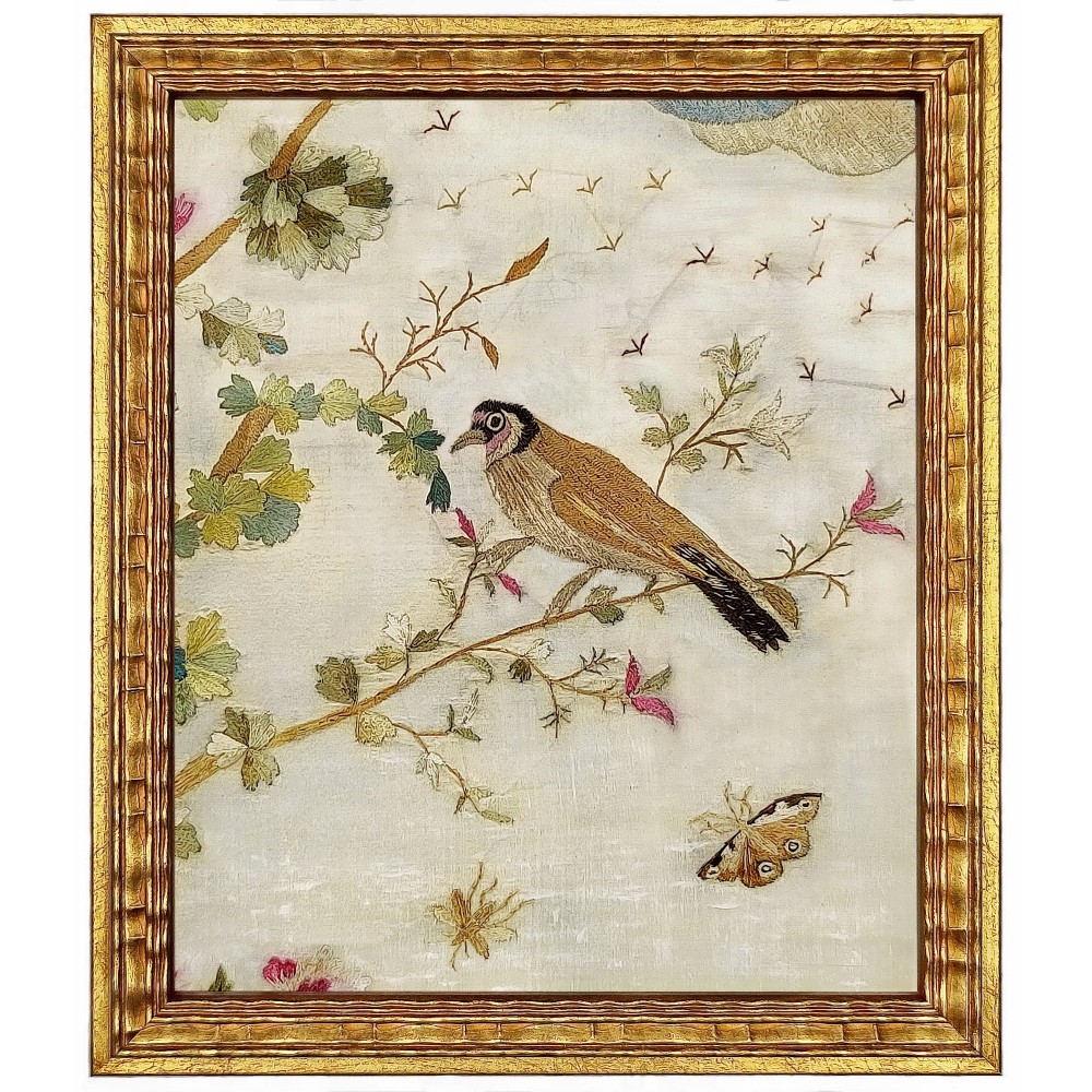 An 18th-century embroidered silk picture framed in giltwood depicting a bird perched on a branch alongside a butterfly.