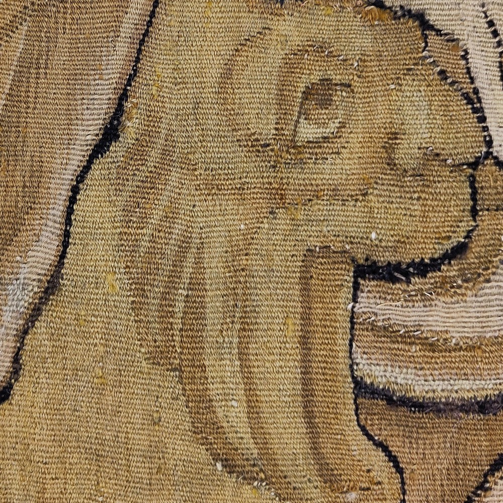 A vertical 16th century Flemish tapestry panel depicting a seated bearded male figure wearing a tall hat and draped robes in blue and gold tones. View III