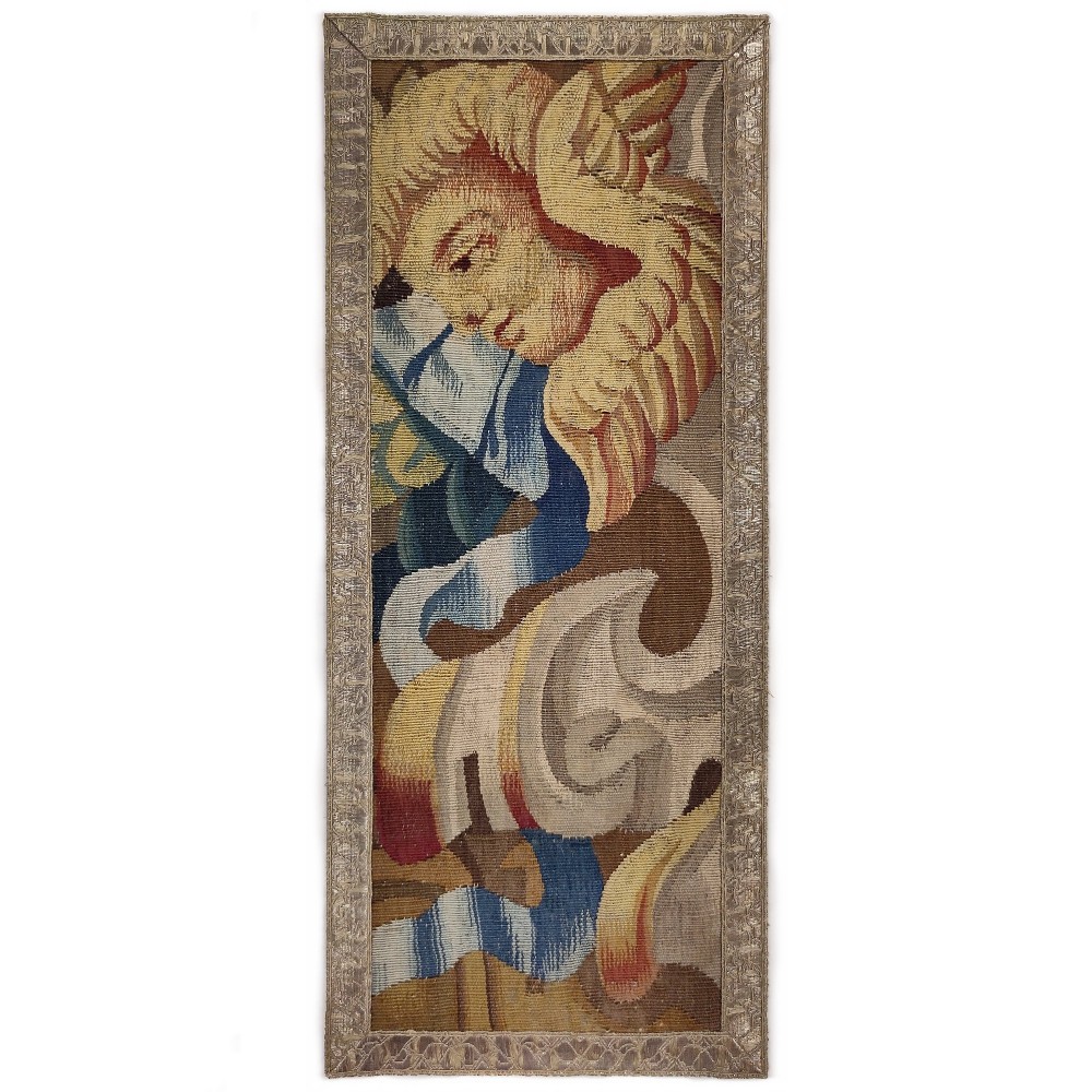 A vertical rectangular 17th-century tapestry fragment featuring a winged cherub head and scrolling acanthus motifs framed by a woven border.