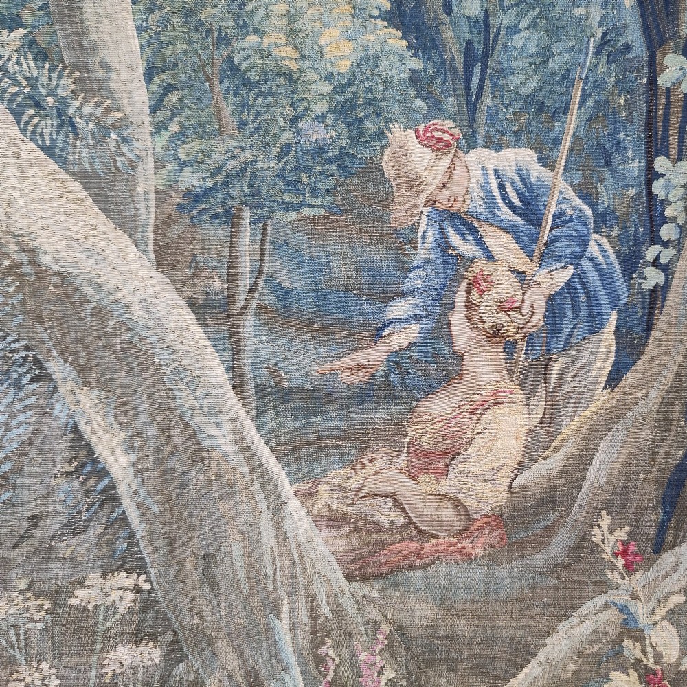 An eighteenth-century Aubusson hand-woven tapestry depicting a pastoral landscape with a river, stone tower, thatched structure, and figures in shades of blue, green, and beige. View II
