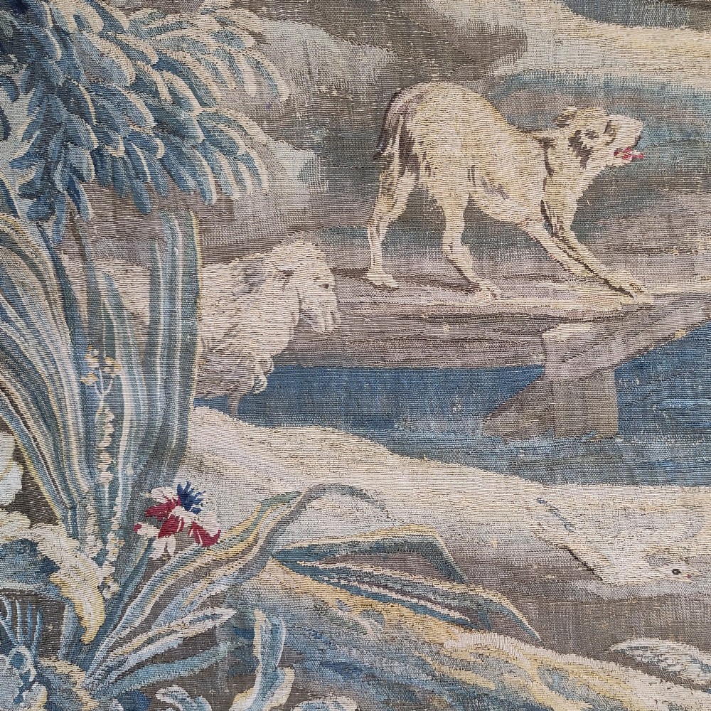 An eighteenth-century Aubusson hand-woven tapestry depicting a pastoral landscape with a river, stone tower, thatched structure, and figures in shades of blue, green, and beige. View IV