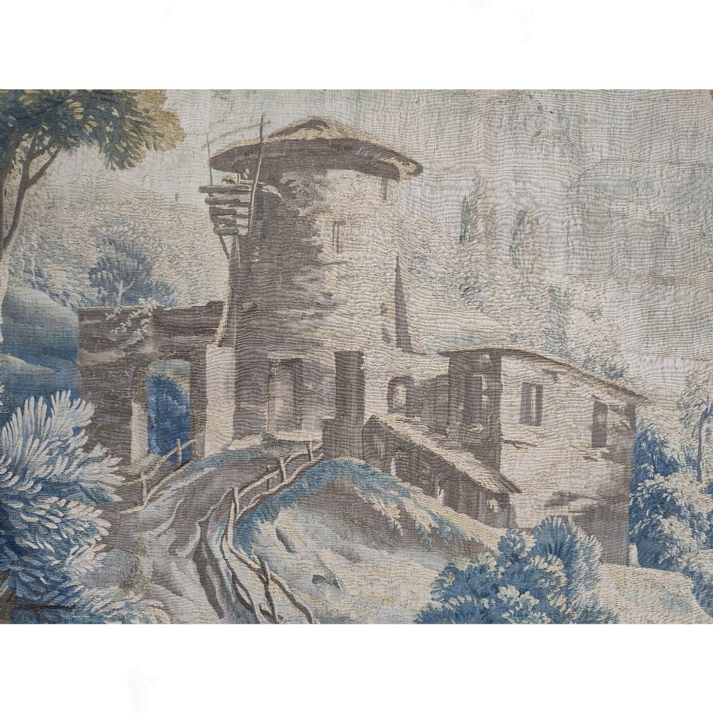 An eighteenth-century Aubusson hand-woven tapestry depicting a pastoral landscape with a river, stone tower, thatched structure, and figures in shades of blue, green, and beige. View VI