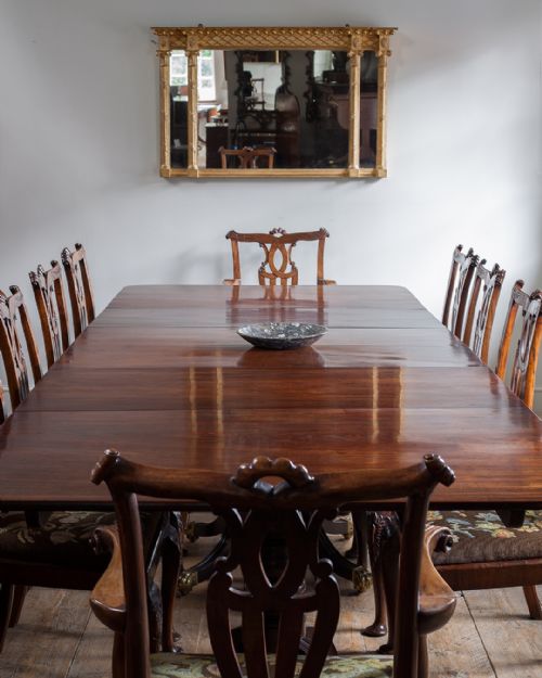 fig 1. A long Regency mahogany triple pedestal dining table with splayed reeded legs and brass paw castors set on a light timber floor.