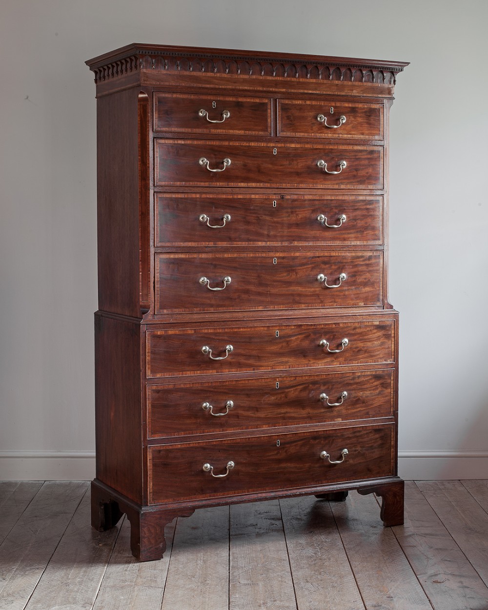 A George III mahogany chest on chest featuring eight drawers with brass swan-neck handles and bracket feet.