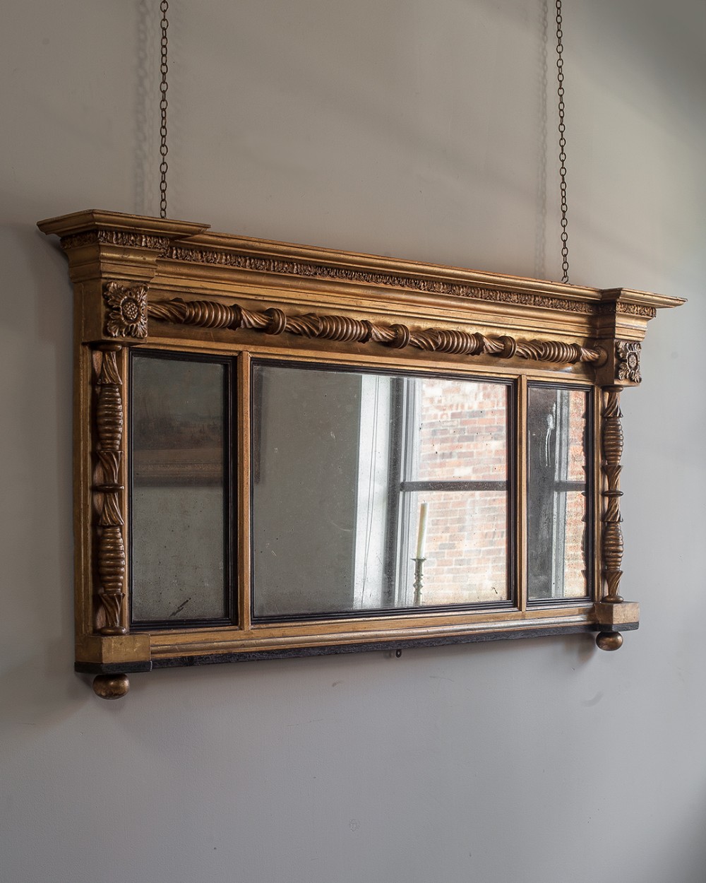 A late Regency giltwood three-plate overmantel mirror featuring rope twist mouldings, fluted columns, and carved corner rosettes.