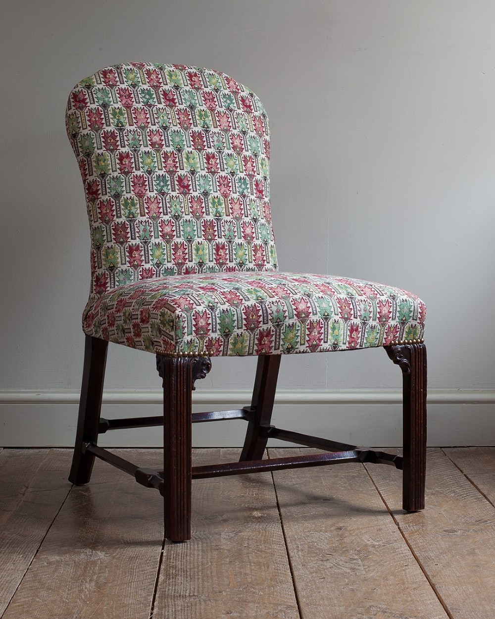 A George III mahogany side chair upholstered in a multi-coloured patterned fabric, featuring fluted front legs and a low stretcher base.