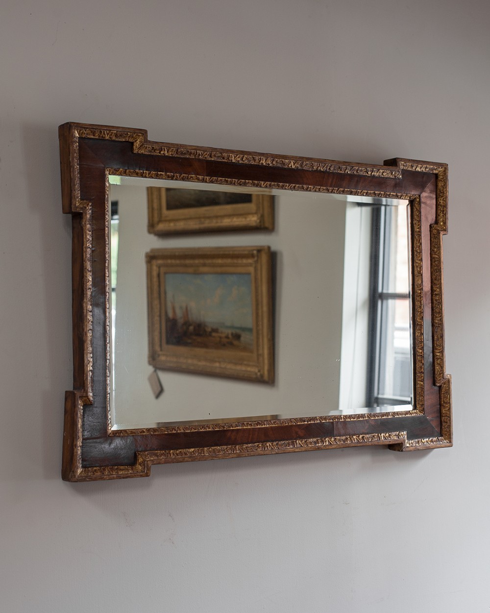 A horizontal 18th-century mahogany wall mirror featuring eared corners and carved parcel gilt inner and outer mouldings.