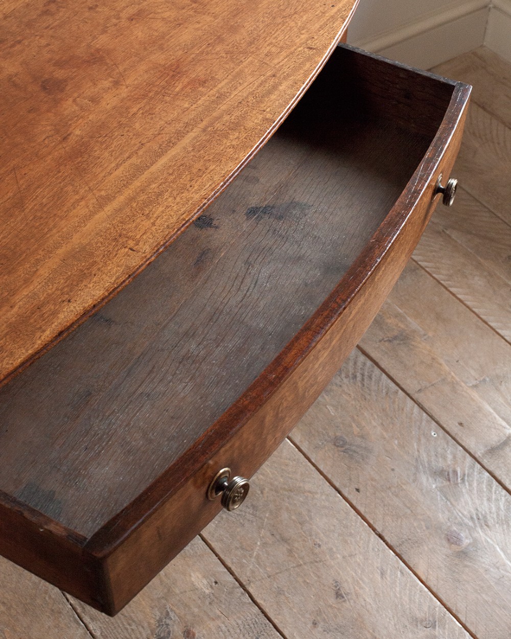 A nineteenth-century mahogany bowfront side table featuring a single drawer with two brass knobs and four ring-turned legs. View II