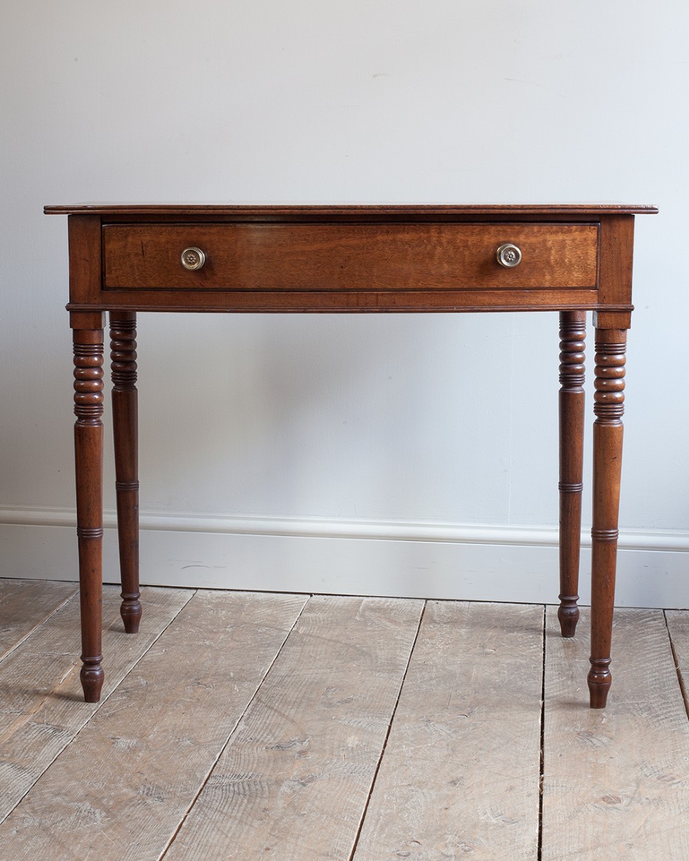 A nineteenth-century mahogany bowfront side table featuring a single drawer with two brass knobs and four ring-turned legs. View VIII