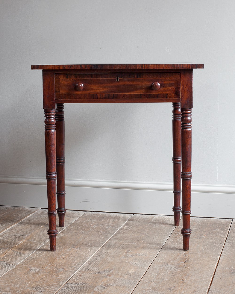 A small George IV mahogany side table featuring a single drawer with wooden knobs and slender turned legs.