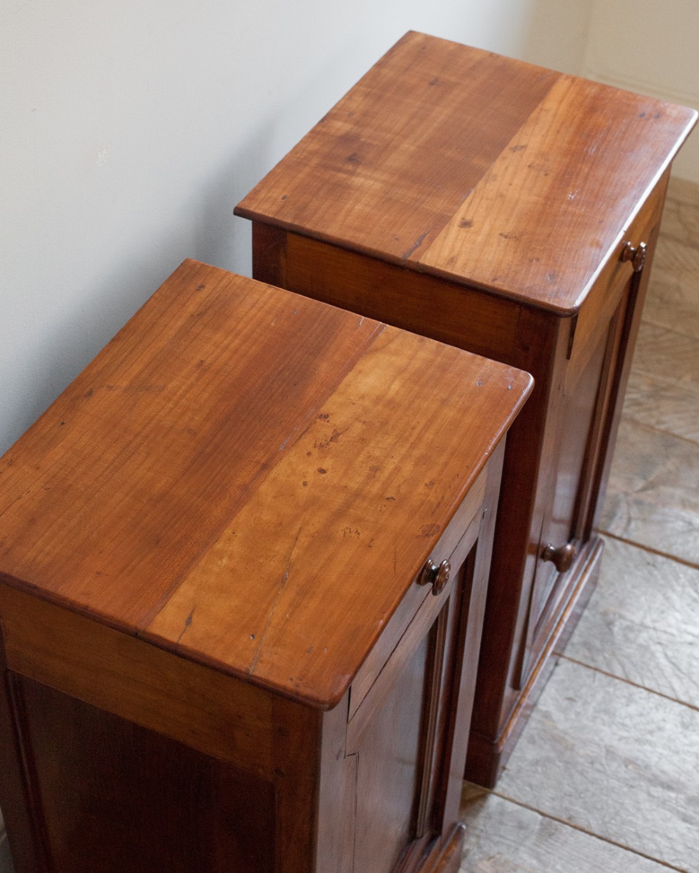 A pair of 19th-century French cherrywood bedside cupboards featuring single top drawers, panelled doors, turned timber knobs, and solid plinth bases. View II