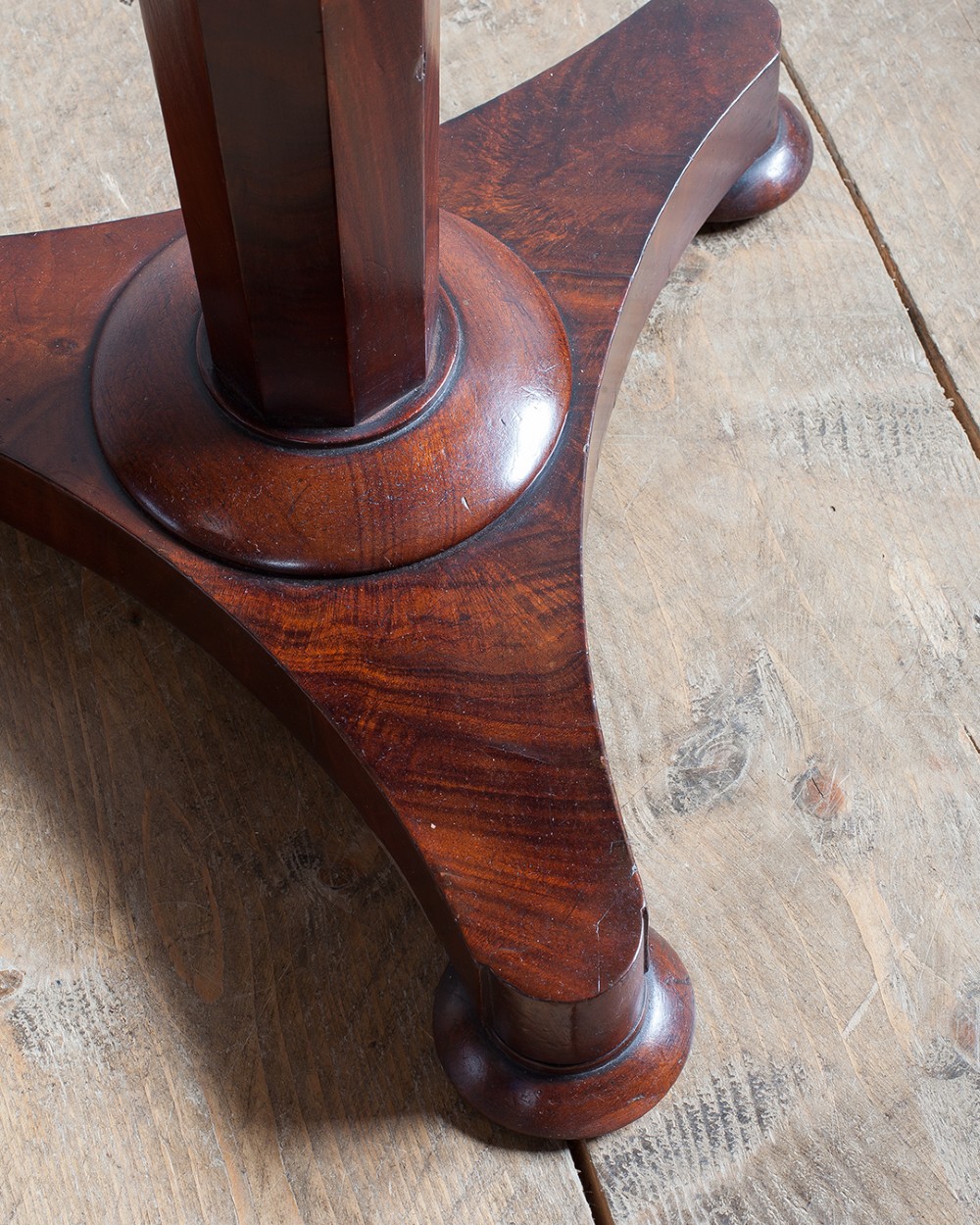 A 19th-century mahogany lamp table featuring a round top supported by a tapered octagonal pedestal stem and a triform base with flattened feet. View V