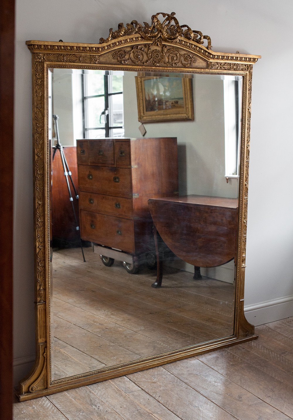 A large 19th-century rectangular giltwood overmantel mirror featuring a ribbon bow knot crest, carved bead moulding, and a flared base. View VII