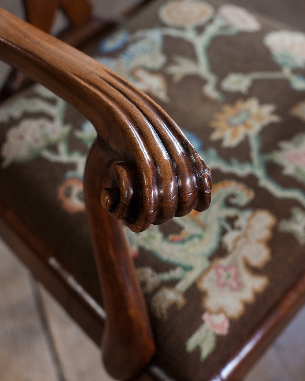 A set of twelve 18th-century carved walnut dining chairs featuring vase-shaped splats, cabriole legs, and floral needlepoint seats. View V