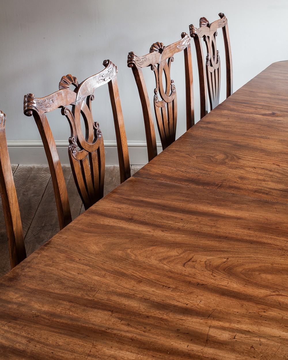A set of twelve 18th-century carved walnut dining chairs featuring vase-shaped splats, cabriole legs, and floral needlepoint seats. View X