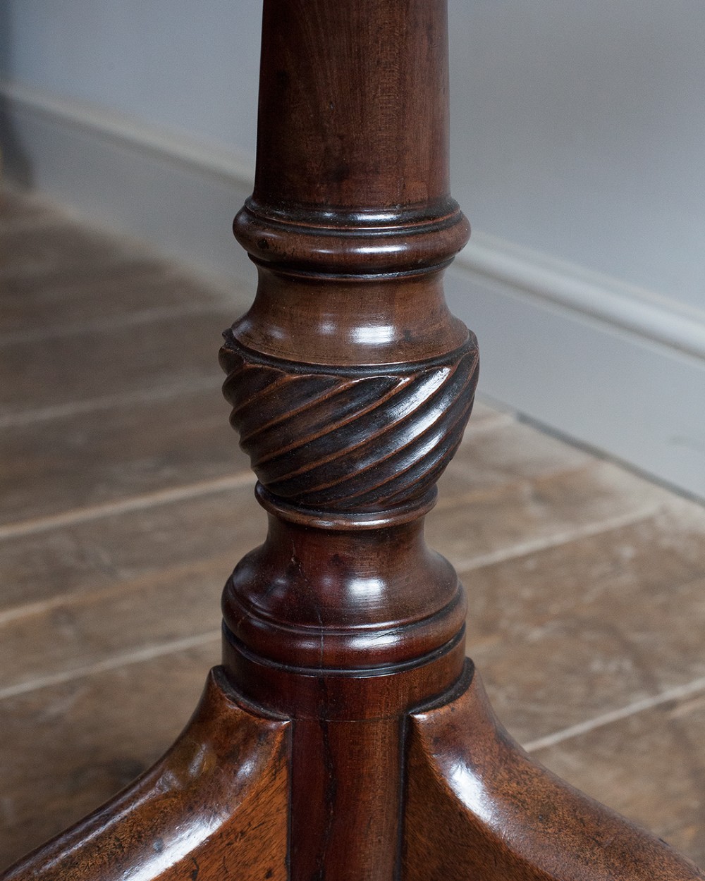 A George III mahogany tripod table featuring a circular top supported by a turned pedestal column with spiral carving and three cabriole legs. View IV