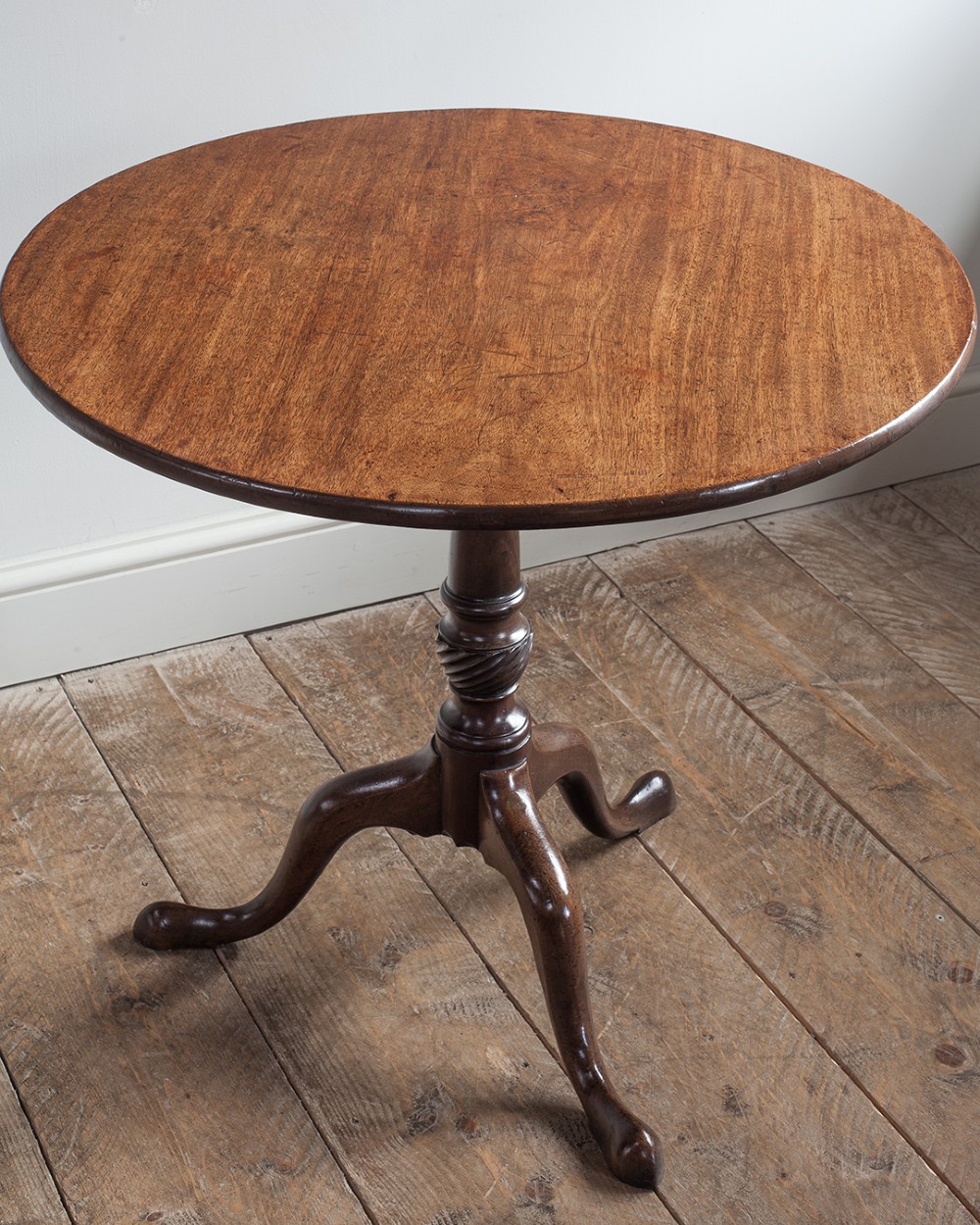 A George III mahogany tripod table featuring a circular top supported by a turned pedestal column with spiral carving and three cabriole legs. View VI