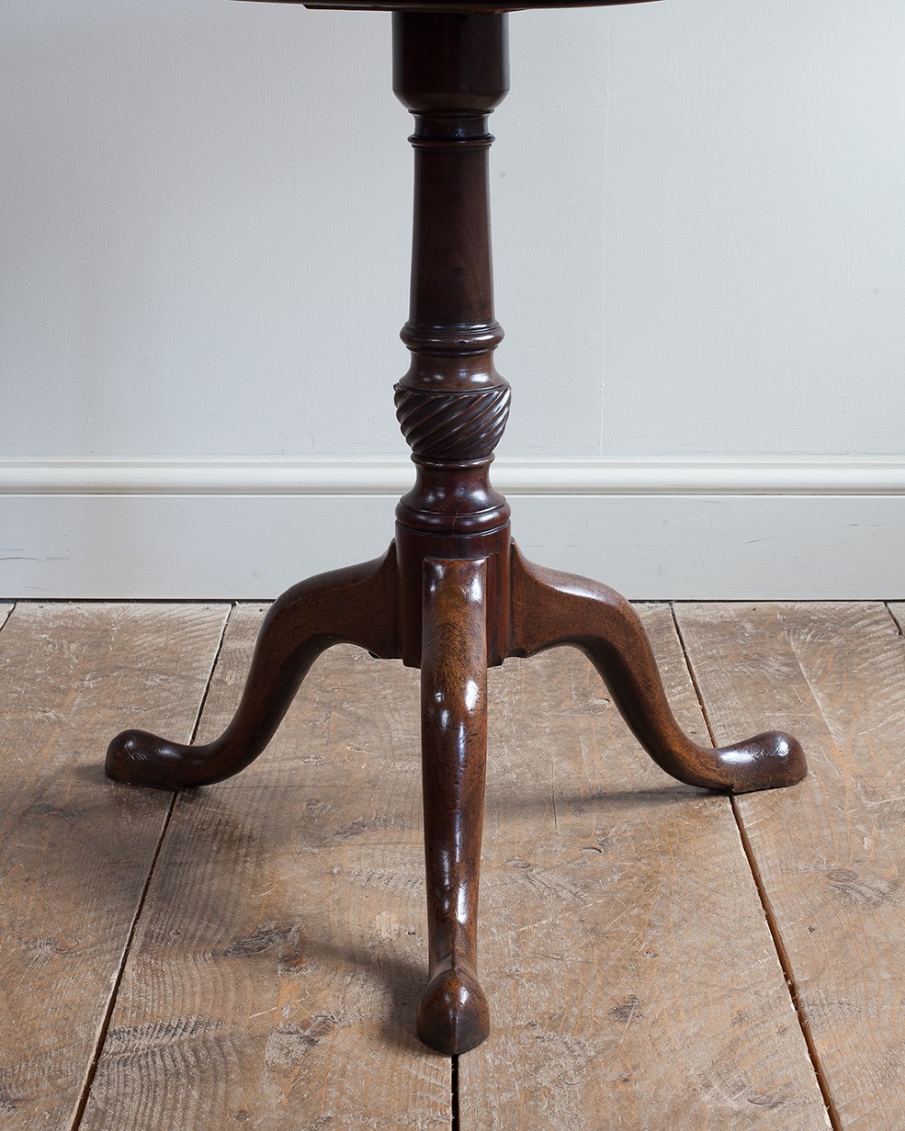 A George III mahogany tripod table featuring a circular top supported by a turned pedestal column with spiral carving and three cabriole legs. View VII